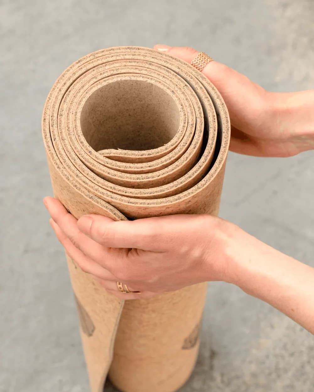 Un tapis de yoga en liège roulé, tenu à deux mains